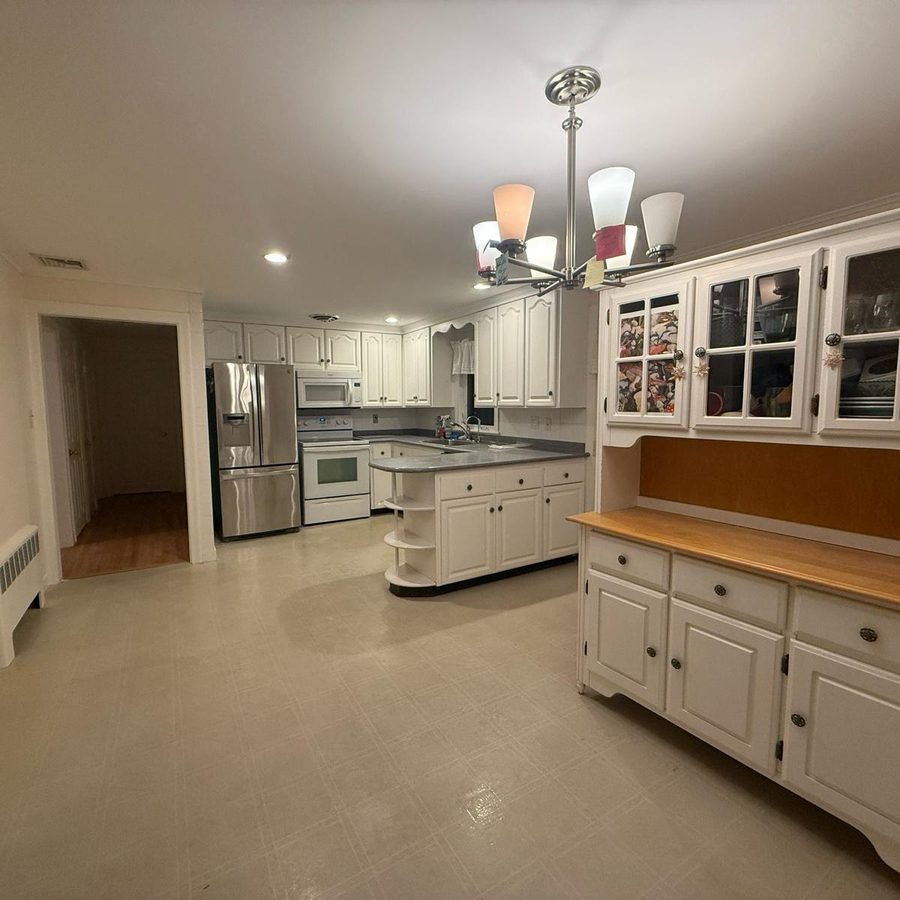 Empty eat-in kitchen with white cabinets, a built-in hutch and a tile floor, ready for the next occupant