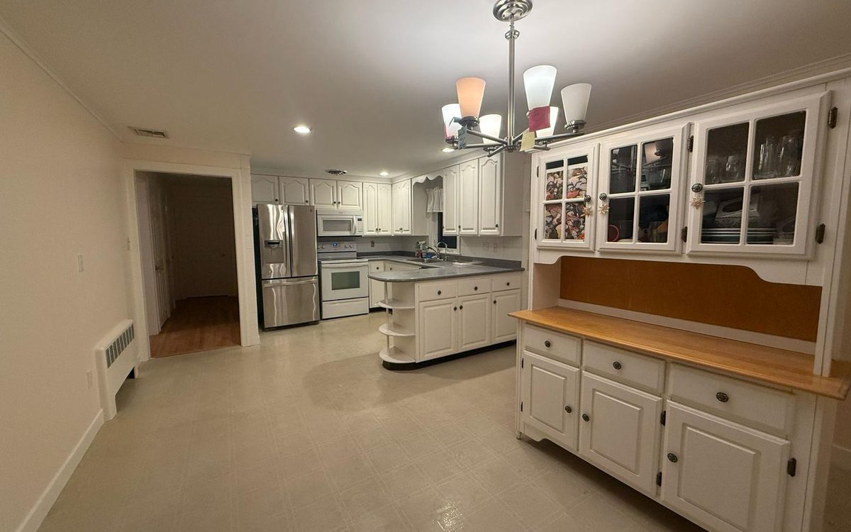 Empty eat-in kitchen with white cabinets, a built-in hutch and a tile floor, ready for the next occupant