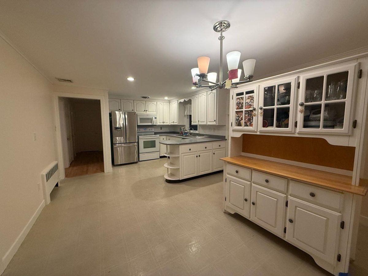 Empty eat-in kitchen with white cabinets, a built-in hutch and a tile floor, ready for the next occupant